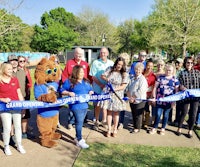 a group of people standing in front of a blue ribbon